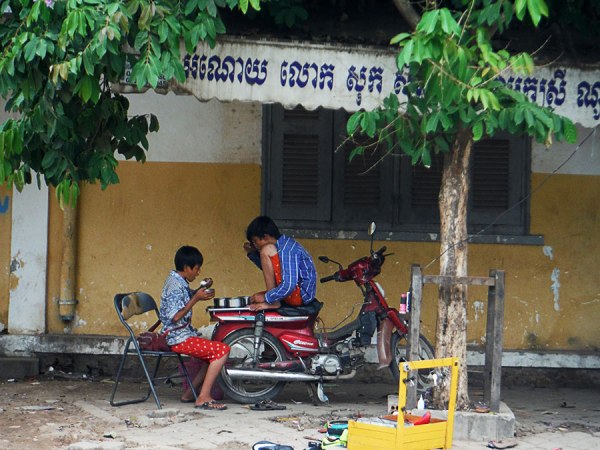 Siem Reap boys using motorbike seat as table